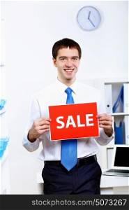 Young businessman at work in office with sale sign