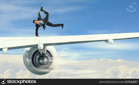 Young businessman breakdancer. Active businessman making handstand on airplane wing