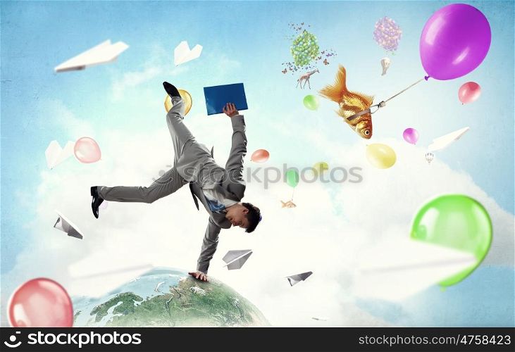 Young businessman breakdancer. Active businessman making handstand on globe. Elements of this image are furnished by NASA