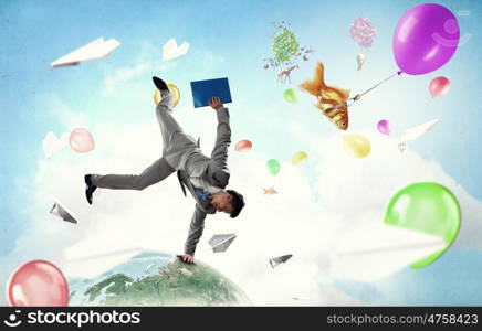 Young businessman breakdancer. Active businessman making handstand on globe. Elements of this image are furnished by NASA