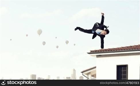 Young businessman breakdancer. Active businessman making handstand on house roof