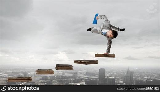 Young businessman breakdancer. Active businessman making handstand on pile of books