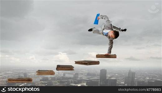 Young businessman breakdancer. Active businessman making handstand on pile of books