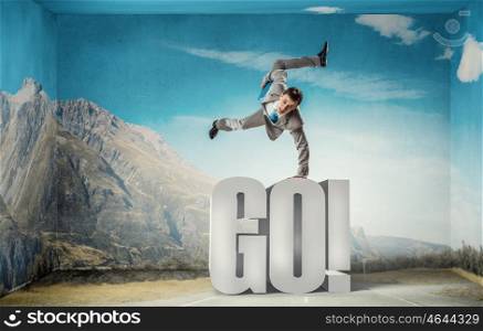 Young businessman breakdancer. Active businessman making handstand on word go