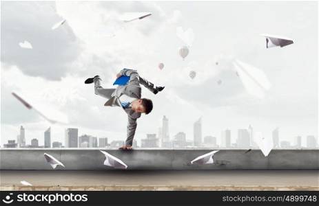 Young businessman breakdancer. Active young businessman or student making handstand on parapet