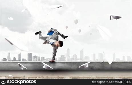 Young businessman breakdancer. Active young businessman or student making handstand on parapet