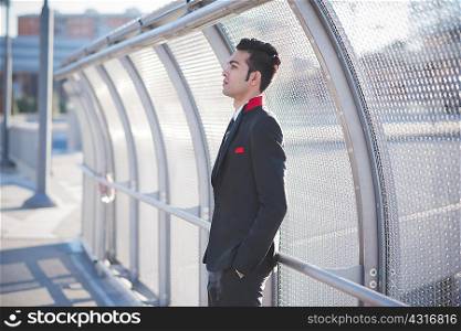 Young businessman by bridge safety fence