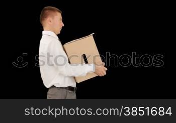 Young businessman carrying a box and falling, against black