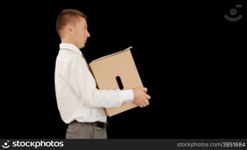 Young businessman carrying a box and falling, against black