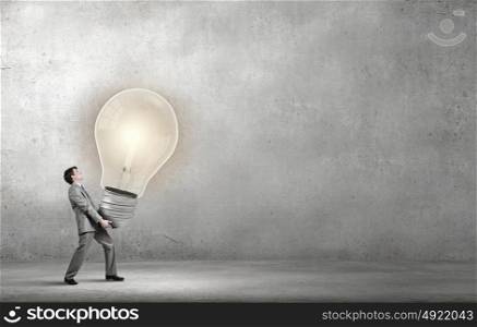 Young businessman carrying in hands big light bulb. Great idea