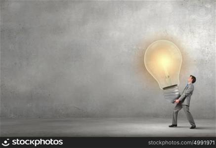 Young businessman carrying in hands big light bulb. Great idea