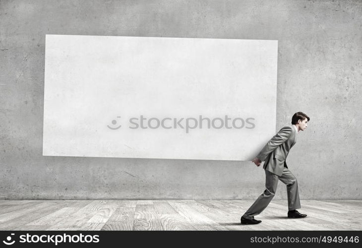 Young businessman carrying white blank banner. Place for text. Banner for your advertisement