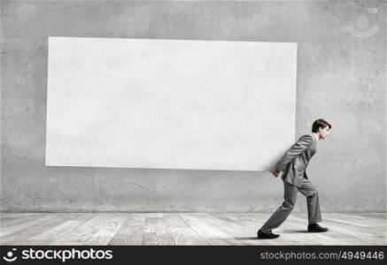 Young businessman carrying white blank banner. Place for text. Banner for your advertisement