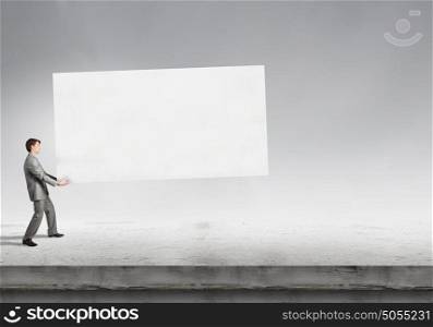 Young businessman carrying white blank banner. Place for text. Banner for your advertisement