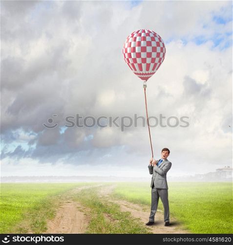 Young businessman caught colorful balloon on lead. Do not let the idea to leave you