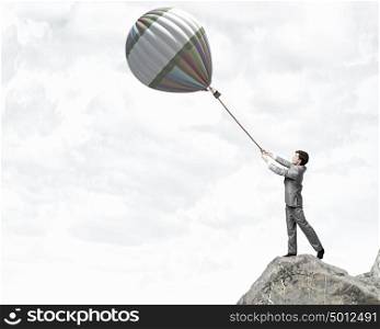 Young businessman caught colorful balloon on lead. Do not let the idea to leave you