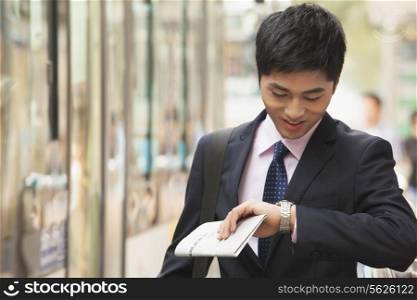 Young Businessman checking the time, waiting for the bus