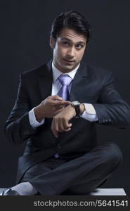 Young businessman checking time against black background