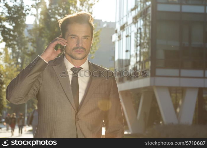 Young businessman conversing on cell phone outdoors