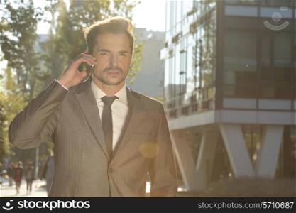 Young businessman conversing on cell phone outdoors