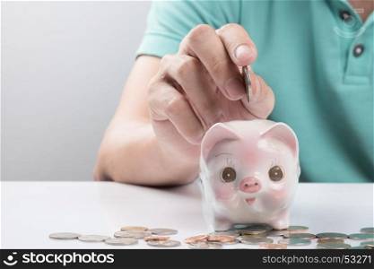 Young businessman depositing money in piggy bank.