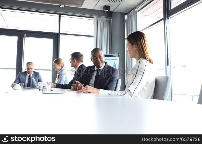Young businessman discussing with female colleague in board room