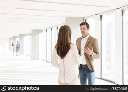 Young businessman discussing with female colleague in new office