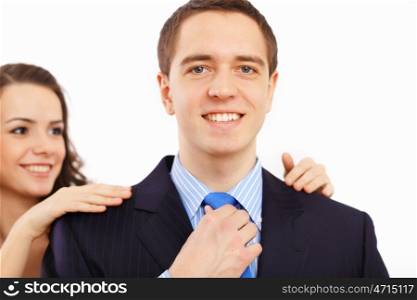 Young businessman dressing at home in the morning. Woman helping to fasten his tie