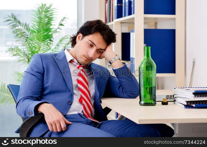 Young businessman employee drinking in the office 