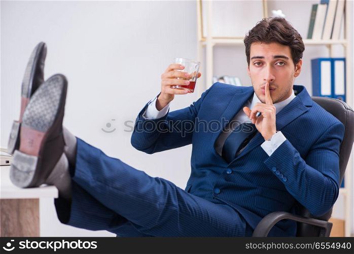 Young businessman employee drinking in the office at desk