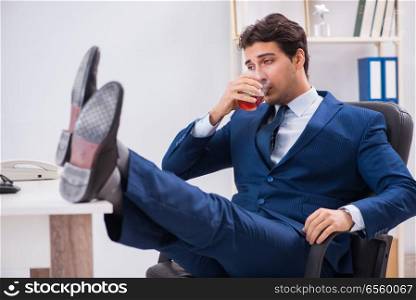 Young businessman employee drinking in the office at desk