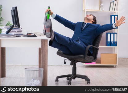 Young businessman employee drinking in the office at desk