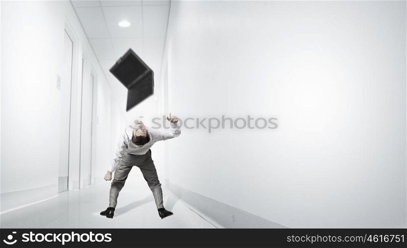 Young businessman evading back from flying laptop