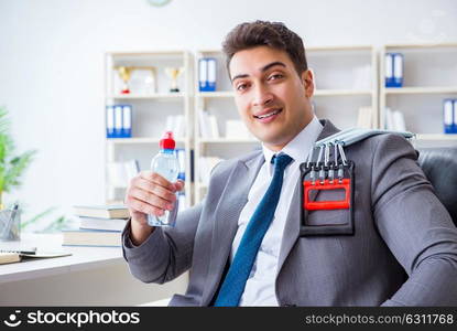 Young businessman exercising with elastic expander in office. The young businessman exercising with elastic expander in office