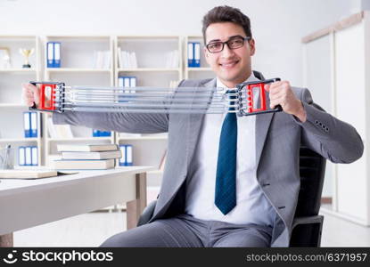 Young businessman exercising with elastic expander in office