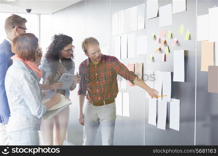 Young businessman explaining document to colleagues in creative office