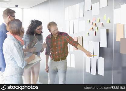 Young businessman explaining document to colleagues in creative office