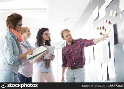 Young businessman explaining document to female colleagues in creative office