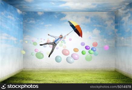 Young businessman flying high in sky on umbrella. Man fly on umbrella