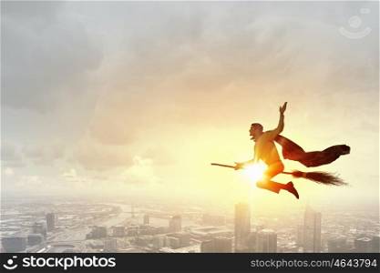 Young businessman flying on broom high in sky. Businessman on broom