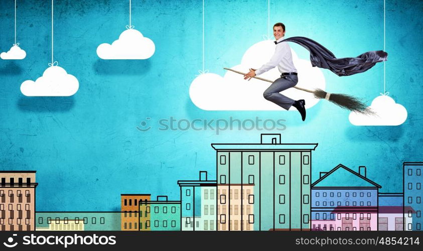 Young businessman flying on broom high in sky. Businessman on broom