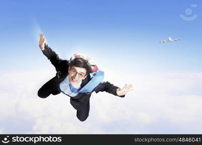 Young businessman flying with parachute on back. Conceptual image of young businessman flying with parachute on back