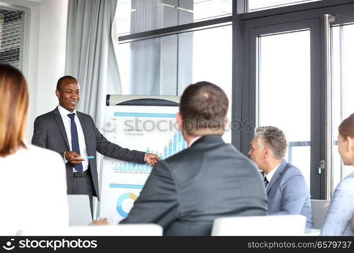 Young businessman giving presentation to colleagues in board room