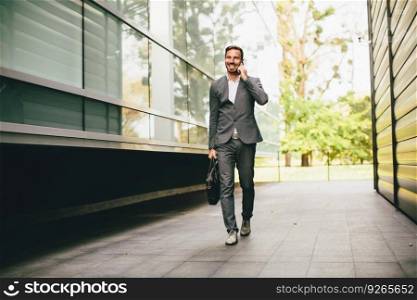 Young businessman going to work, talking on mobile phone and carries a briefcase in hand