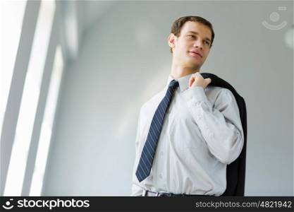 Young businessman. Handsome smiling businessman holding jacket on his shoulder