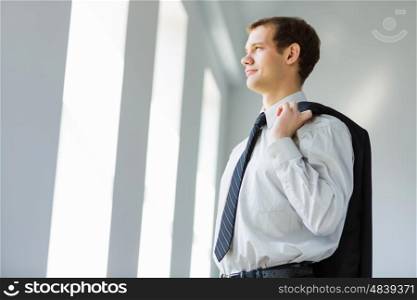 Young businessman. Handsome smiling businessman holding jacket on his shoulder