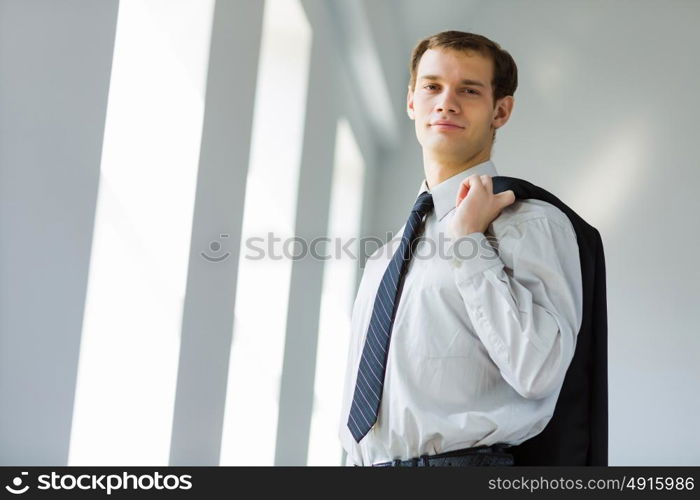 Young businessman. Handsome smiling businessman holding jacket on his shoulder