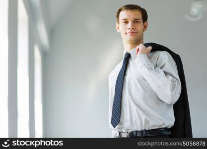 Young businessman. Handsome smiling businessman holding jacket on his shoulder