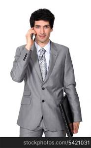young businessman holding a briefcase and talking on his cell