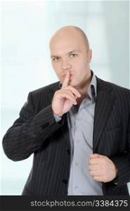 young businessman holding a finger to his mouth.
